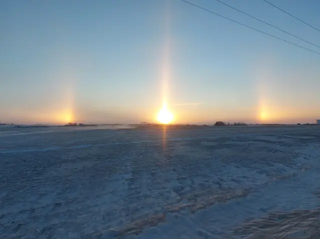 Sun dogs over snowy farmland